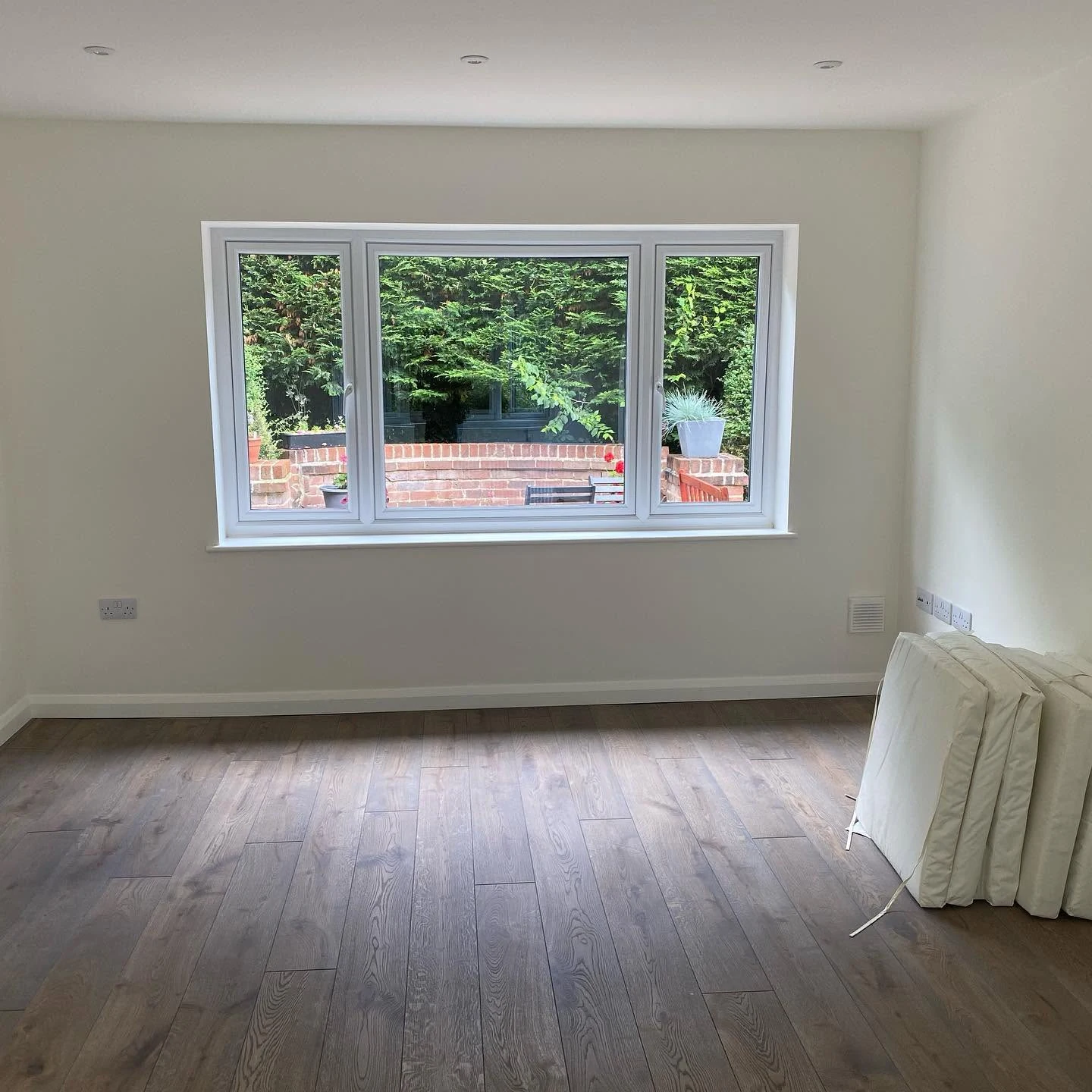 A finished reception room with a large new window over the garden
